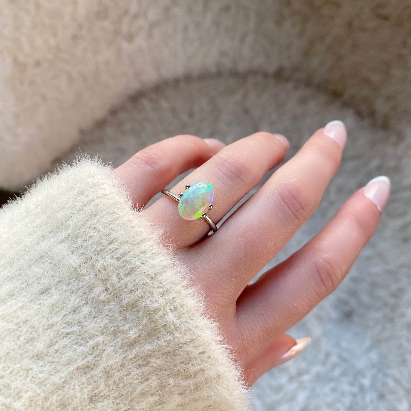 a 2.03 ct oval opal shown on a light skinned left hand in morning sunlight