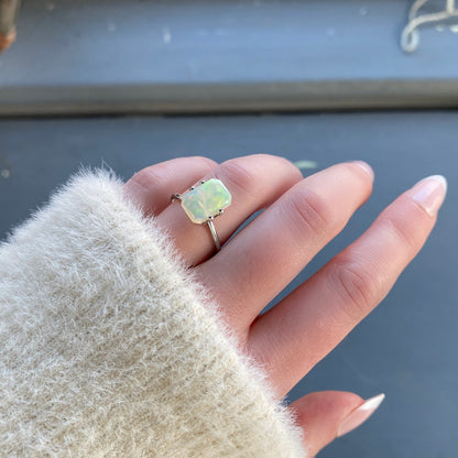 a 2.26 ct emerald cut opal is shown in a temporary ring mount in diffused winter sunflight