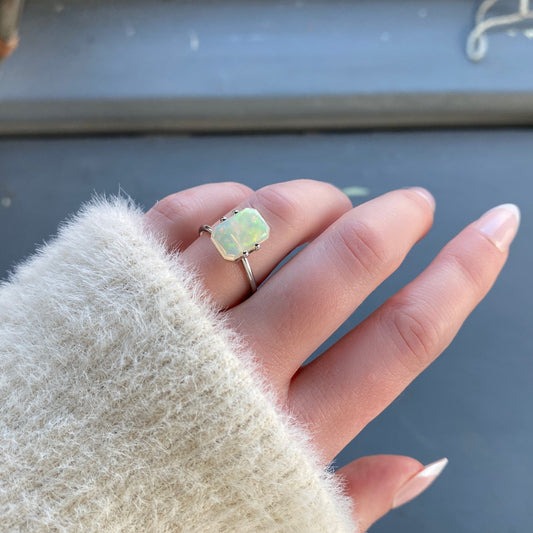 a 2.26 ct emerald cut opal is shown in a temporary ring mount in diffused winter sunflight