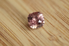 Cushion Cut pink Zircon gemstone on a wooden surface