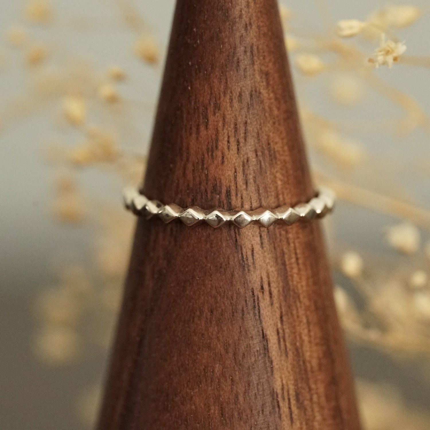 a white gold ring rests on a wood finger display