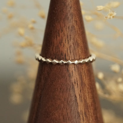 a white gold ring rests on a wood finger display