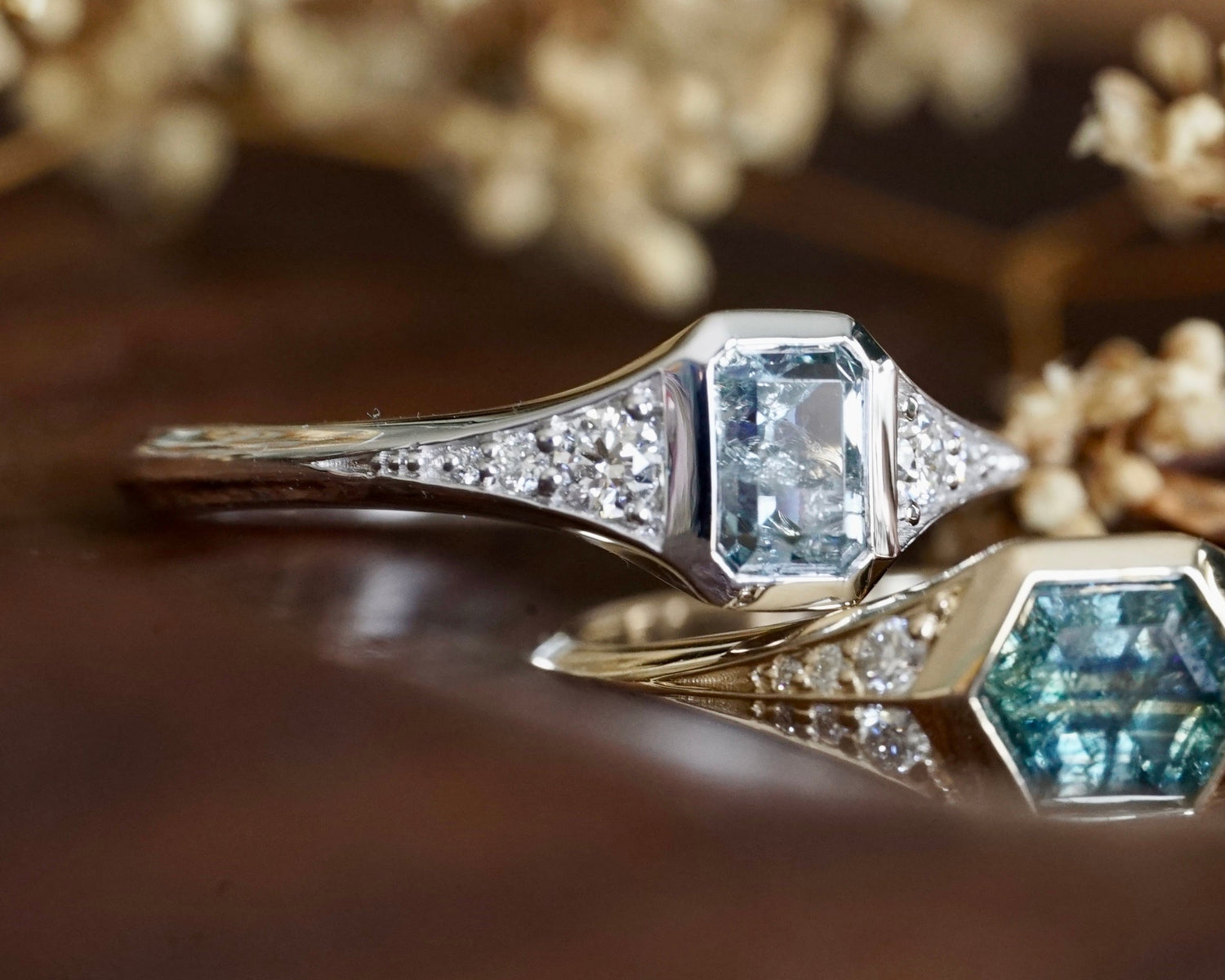 Close-up of two diamond rings with a blurred floral background