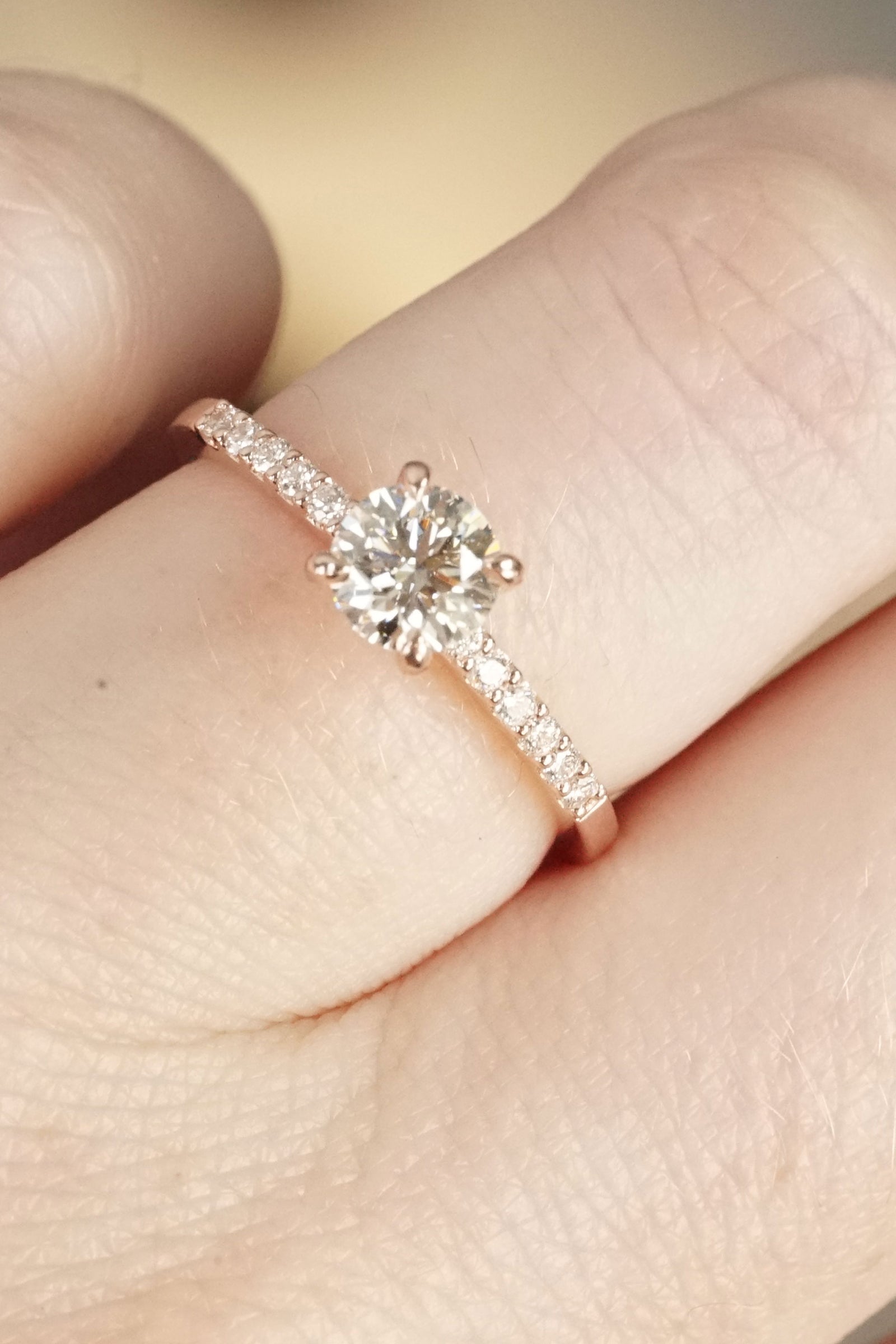 a rose gold and diamond ring on a light skin tone hand