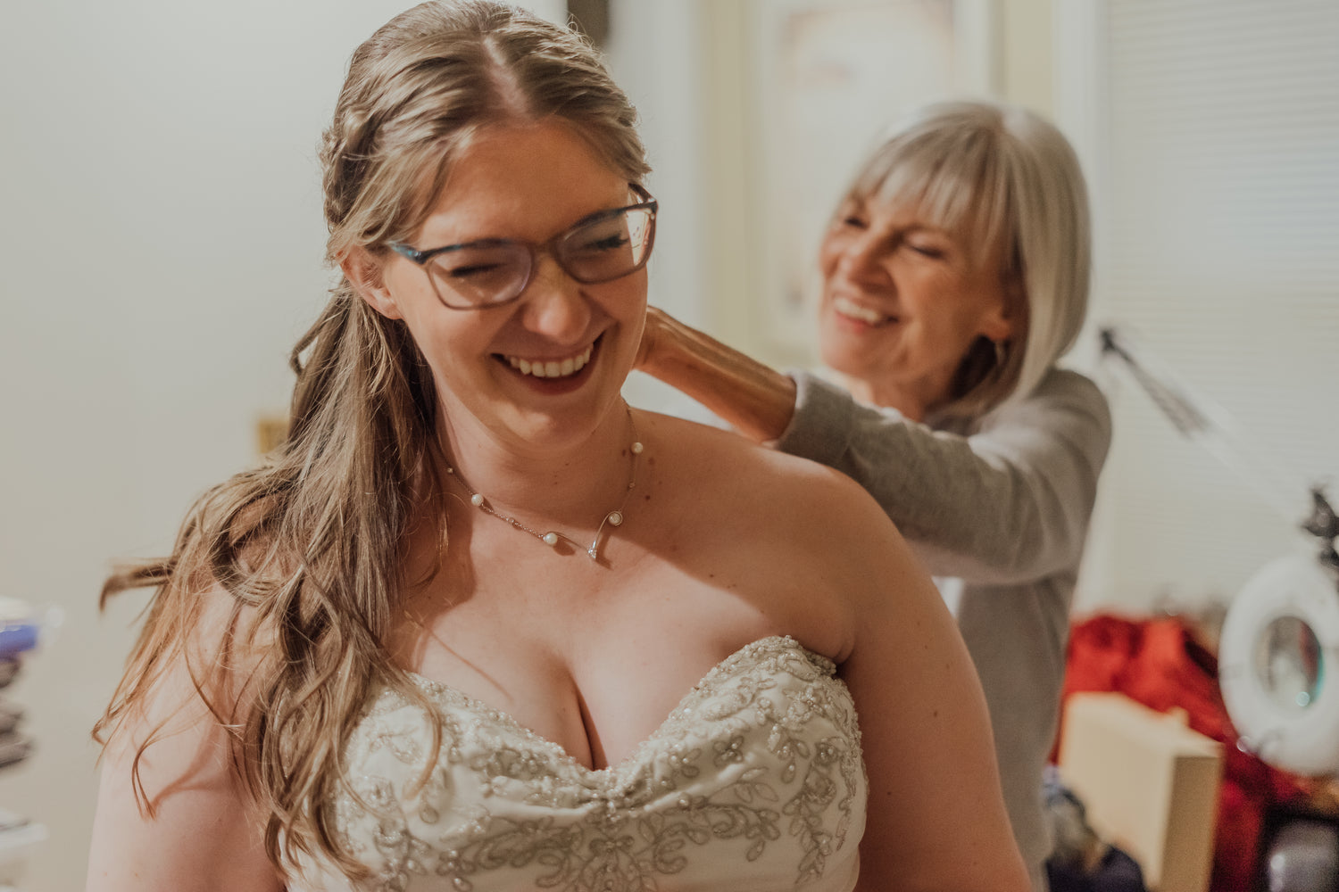 a beautiful bride receives a custom necklace from her mother on her wedding day. Photograph by Cara Noelani Photos LLC