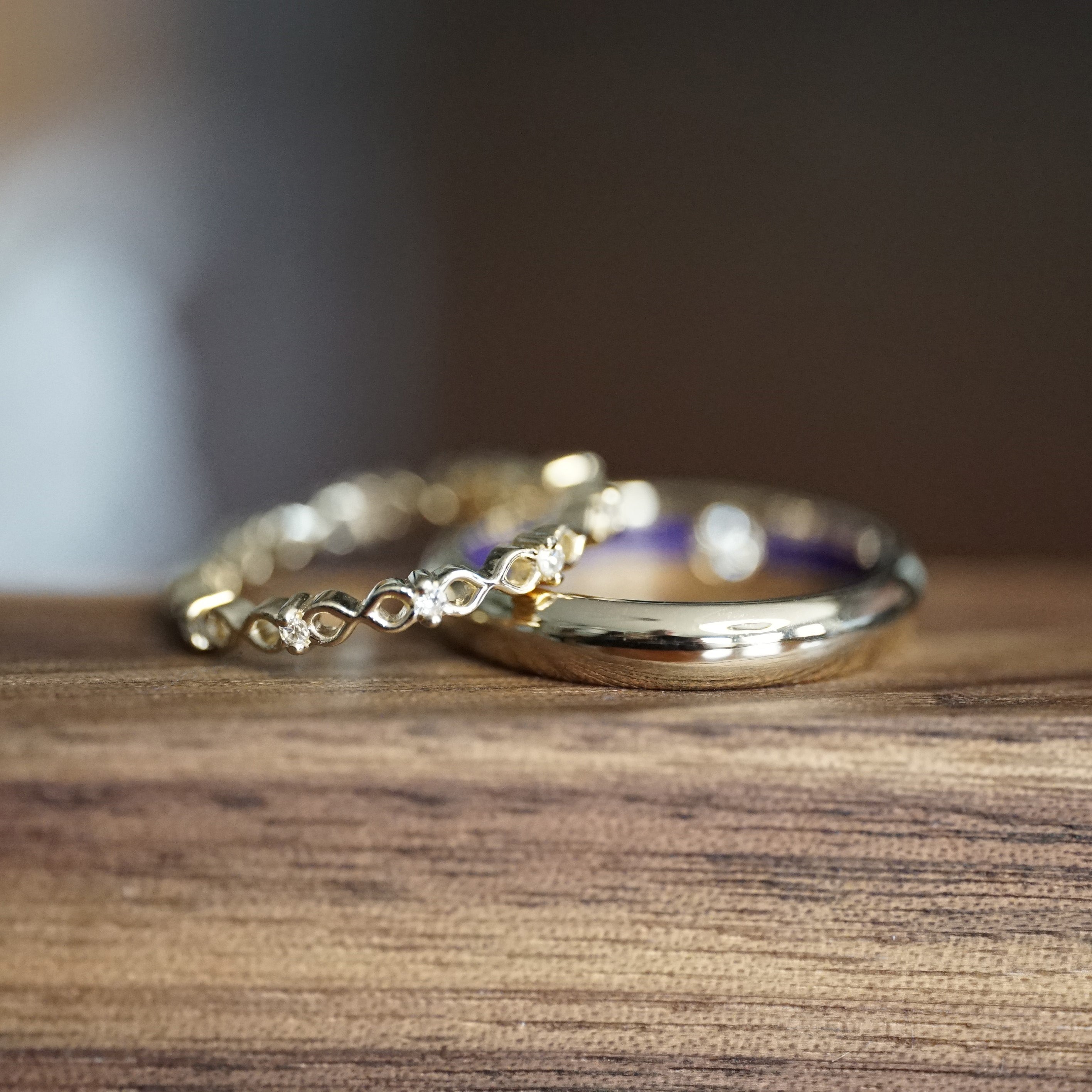 a macro photo of a pair of yellow gold wedding bands on a wood display