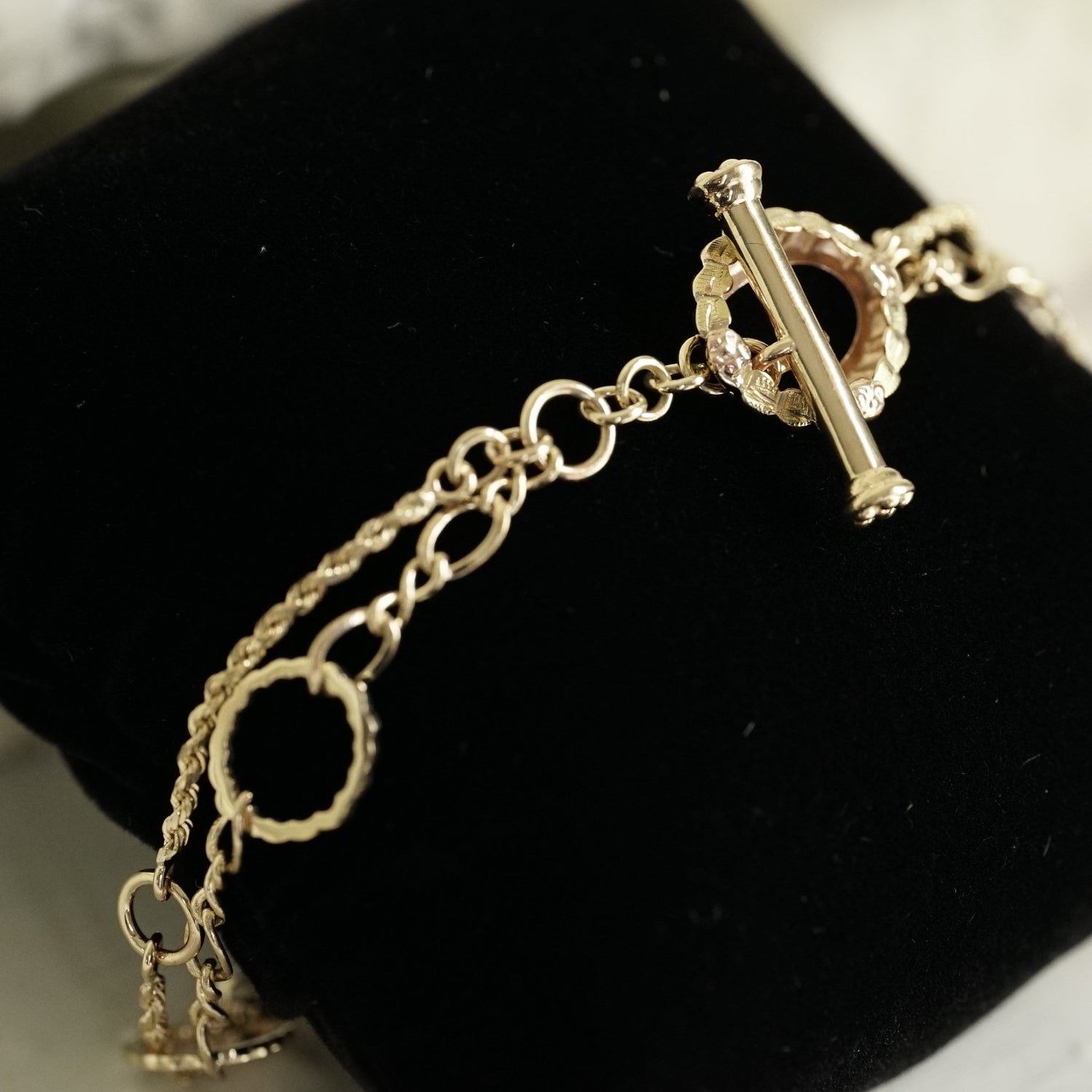 a yellow gold bracelet with heirloom and newly created links displayed on a soft black velvet pillow