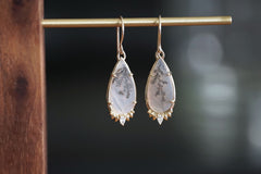 Teardrop-shaped earrings with gold accents on a dark background