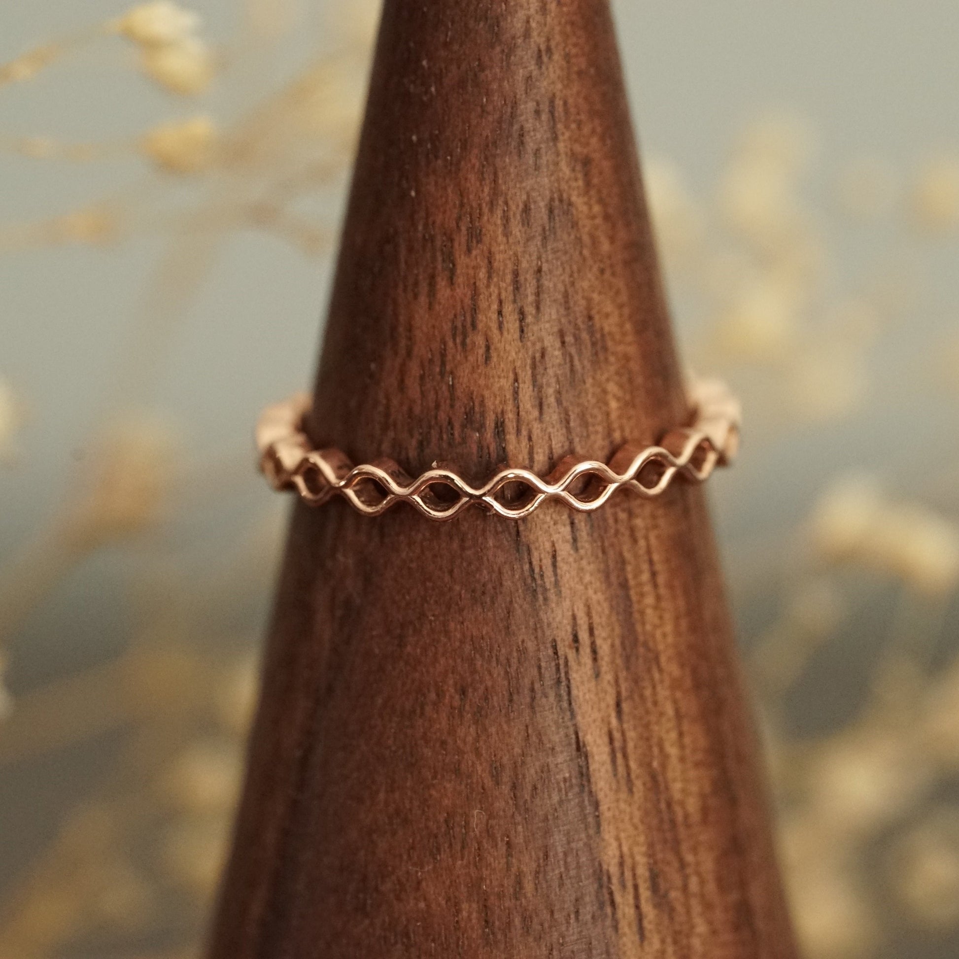 a rose gold band on a wood finger display