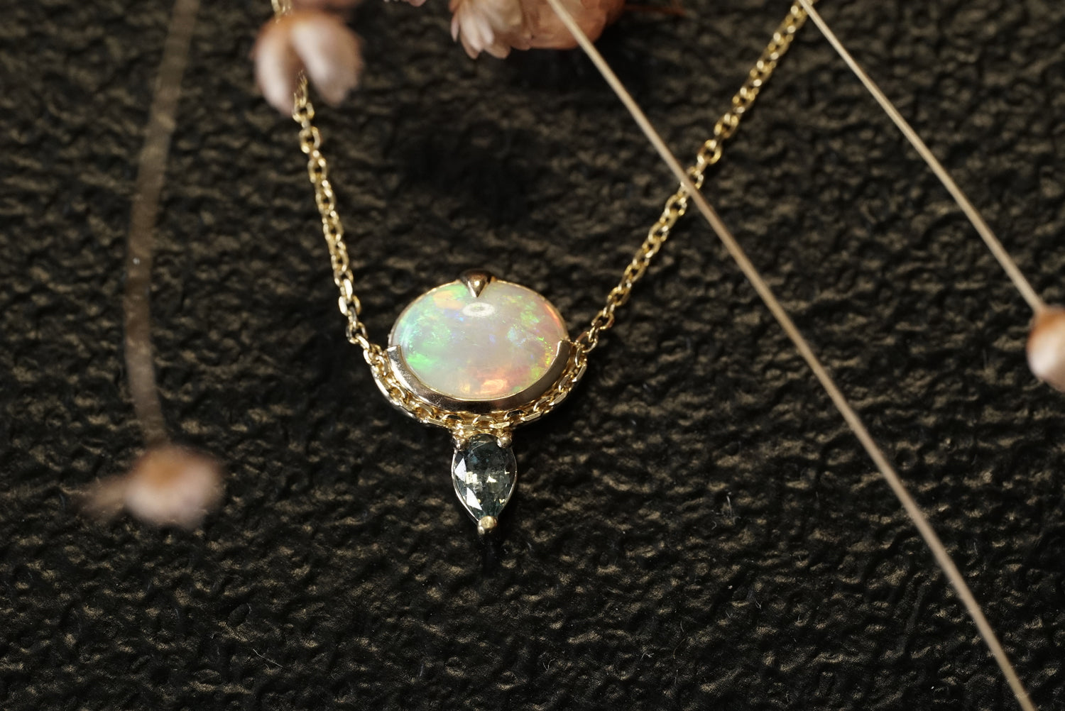Gold necklace with an opal pendant on a textured black background