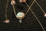 Gold necklace with an opal pendant on a textured black background