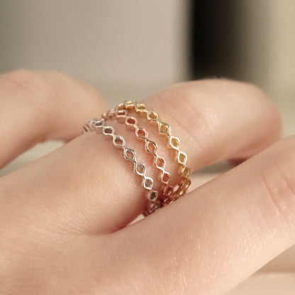 stacking rings in white yellow and rose gold shown on a light skinned left hand