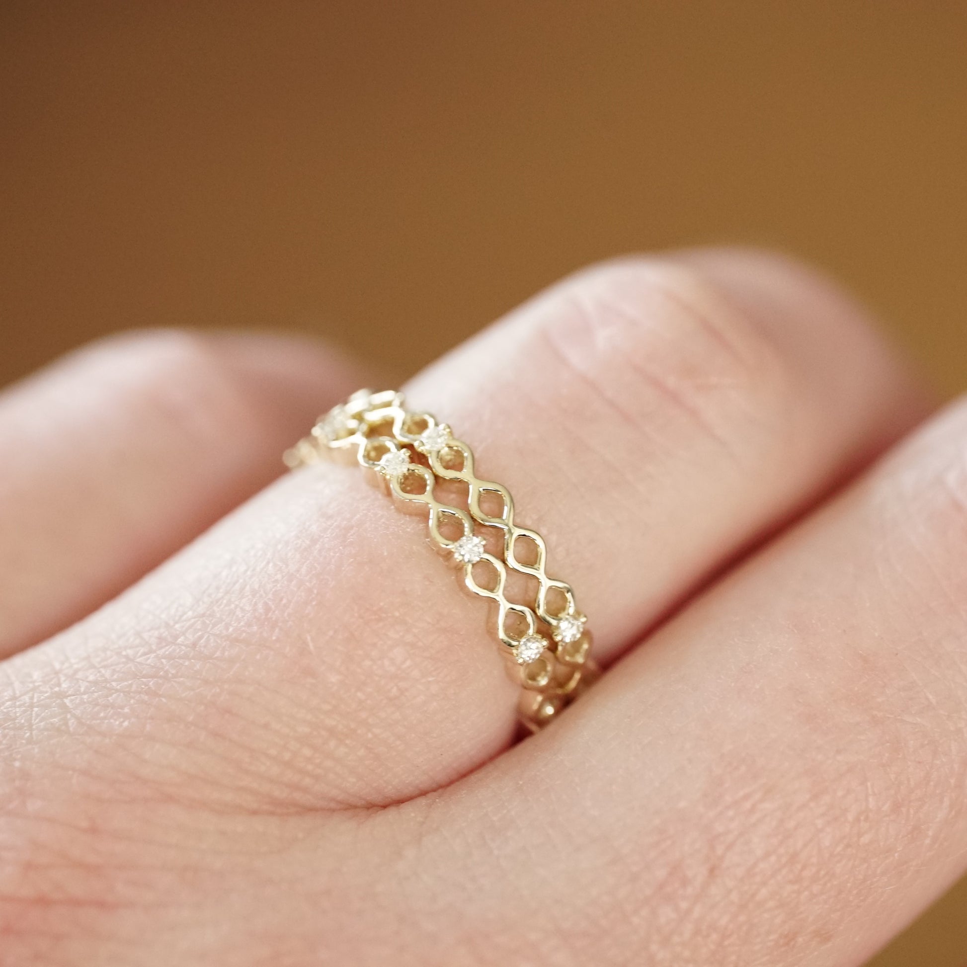 two yellow gold and diamond bands are shown on a light skinned left hand