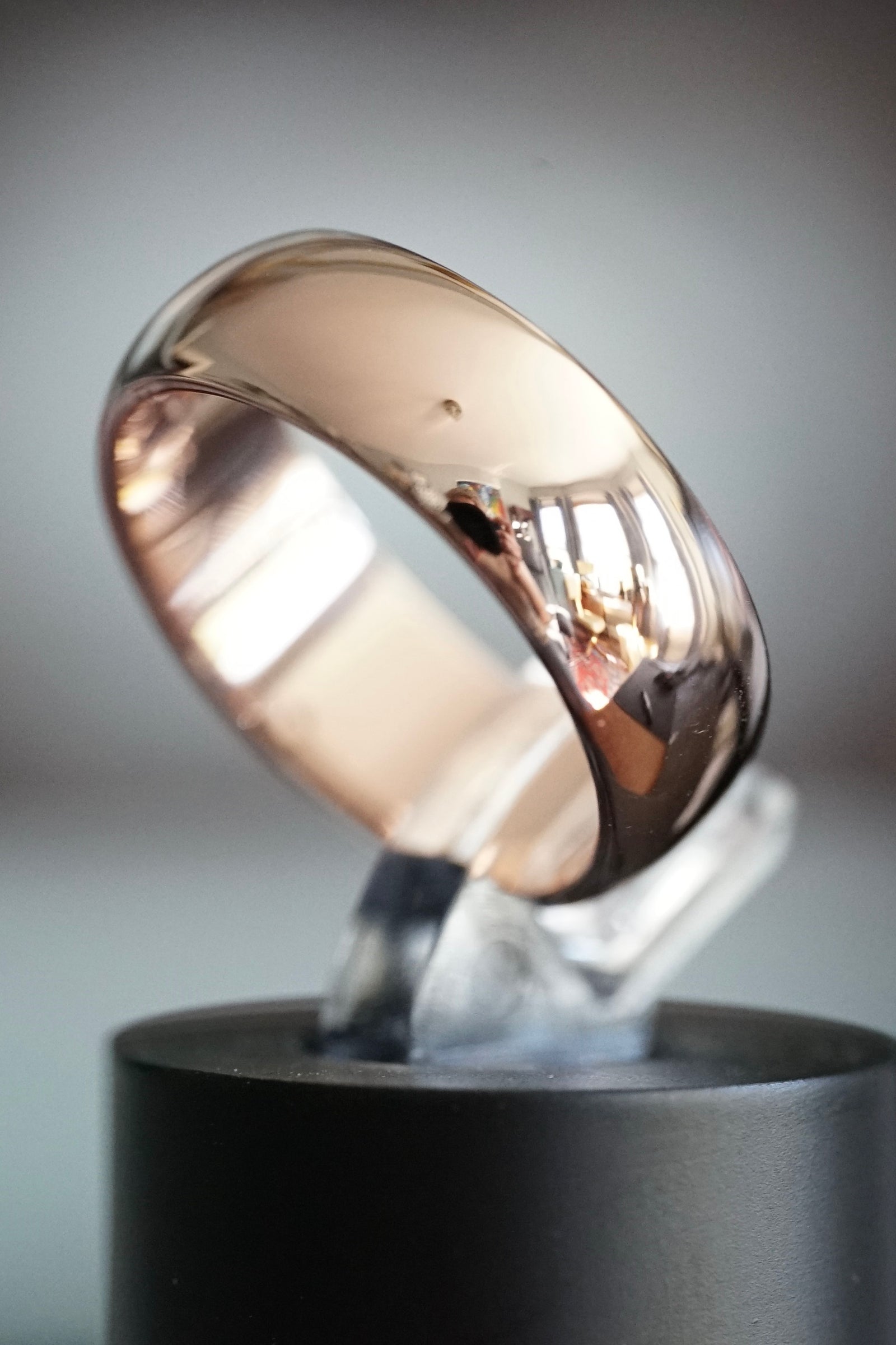 a rose gold wedding band reflecting the photographer taking a picture