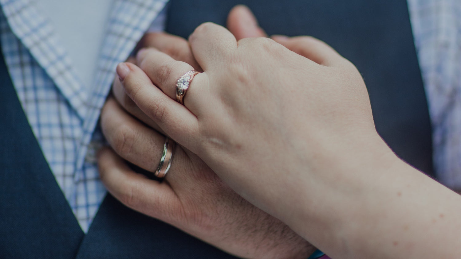A bride and groom hold hands on their wedding day and show off their custom wedding set. Photograph by Cara Noelani Photos LLC