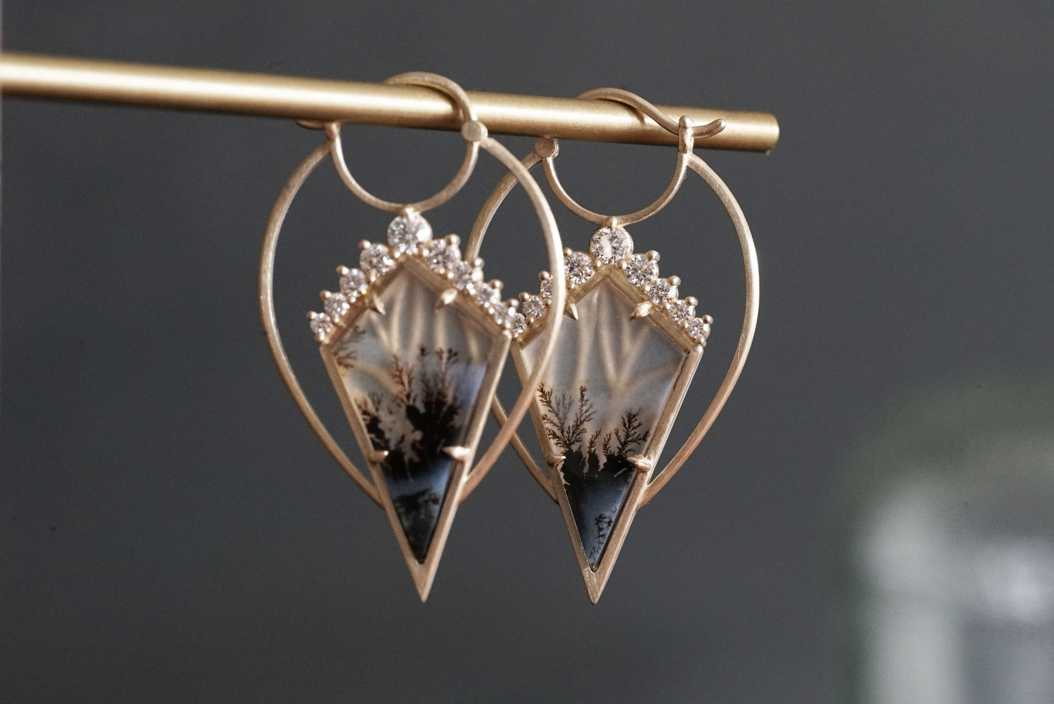 A pair of yellow gold, agate, and diamond drop earrings on a grey background