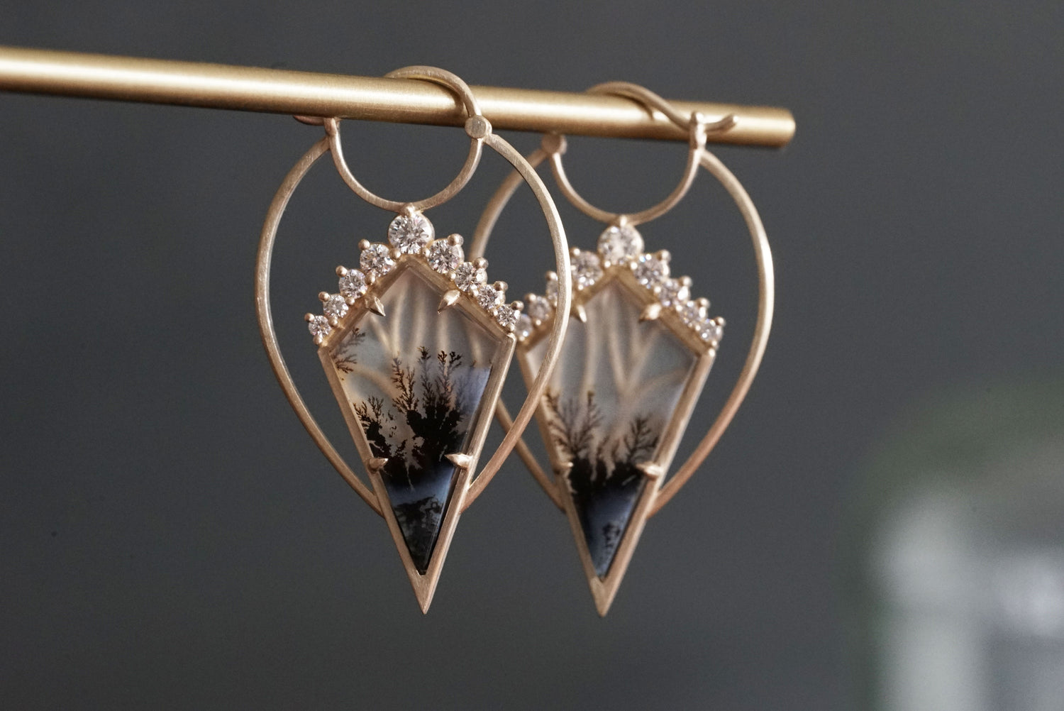 A pair of yellow gold, agate, and diamond drop earrings on a grey background
