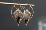 A pair of yellow gold, agate, and diamond drop earrings on a grey background