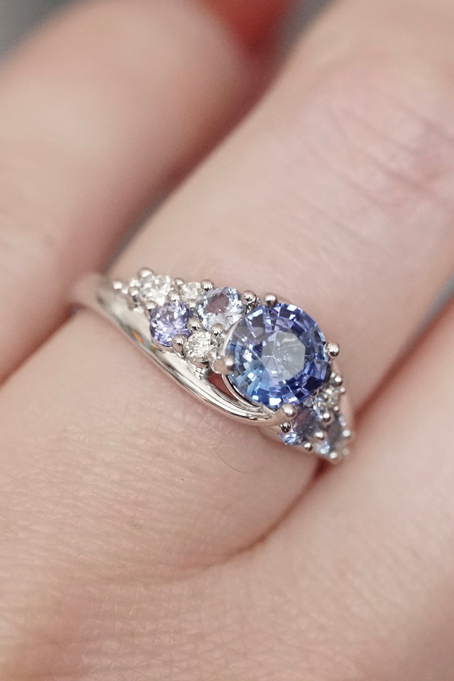 a white gold blue sapphire and diamond ring on a light skin tone hand