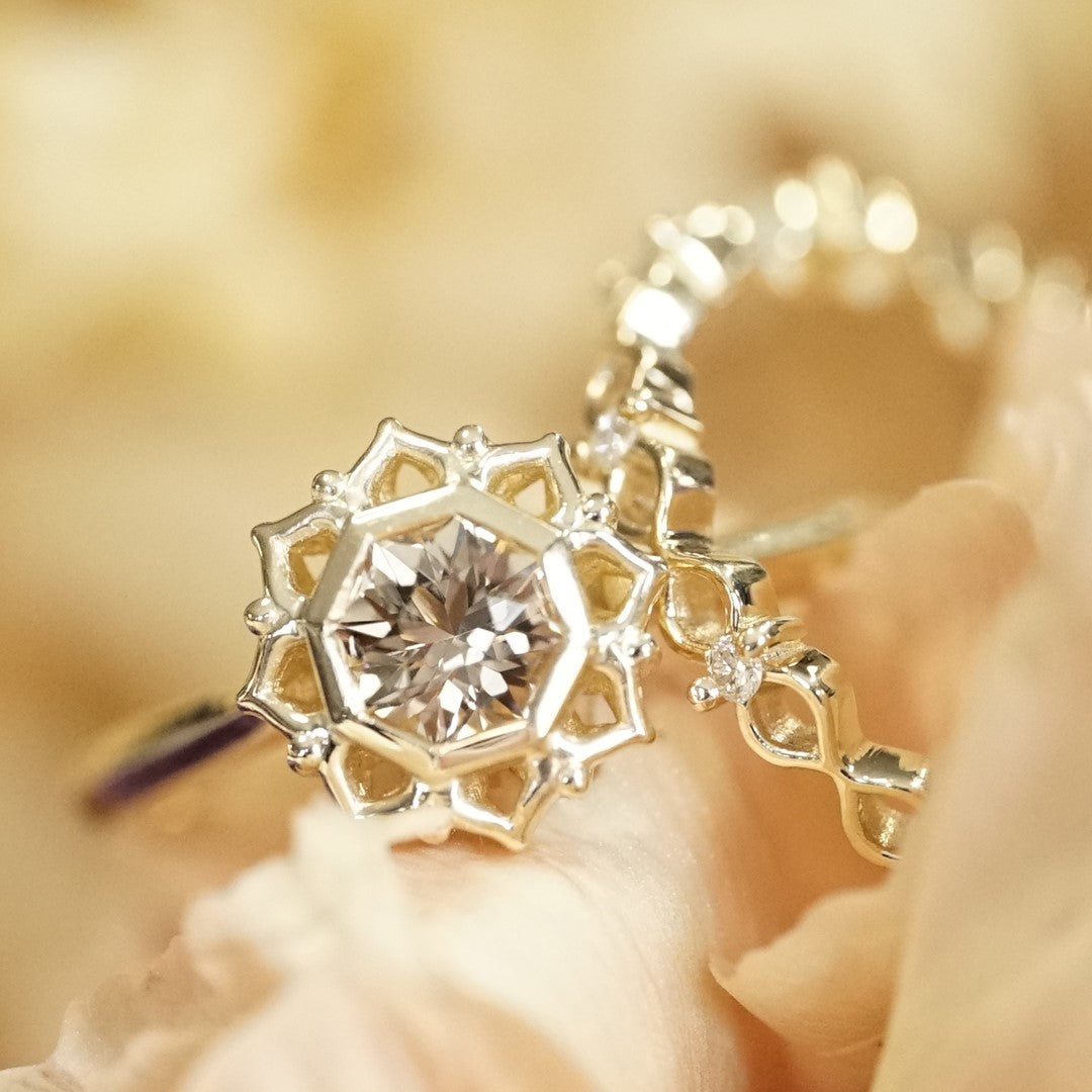 an octagon shape golden tourmaline is bezel set in a floral inspired setting and paired with a sweet diamond wedding band, the set is displayed on a yellow flower
