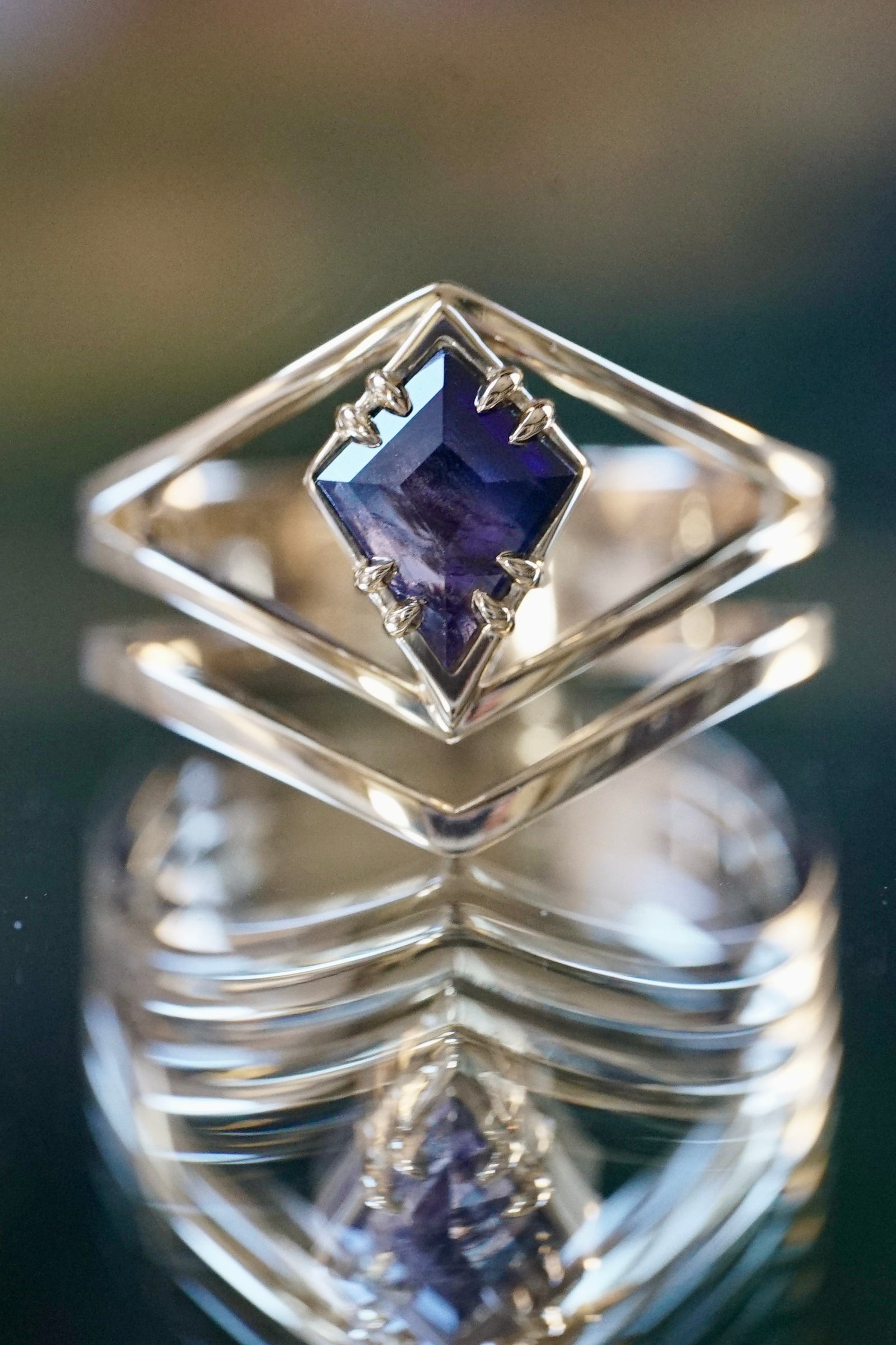 a yellow gold and kite shaped sapphire multi band engagement ring on a reflective background