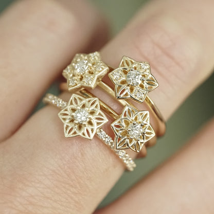 a set of 4 daffodil inspired yellow gold and diamond rings of on a light skinned left hand