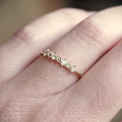 a yellow gold ring with 3 flower elements and 4 diamonds on a light skinned left hand