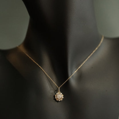 a yellow gold pendant with a large diamond center stone and 5 diamond accents in a floral design on an open link chain displayed on a minikin for scale