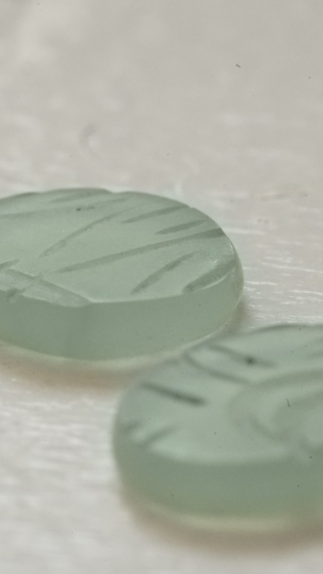 two custom cut jade cabochons on a glossy white background