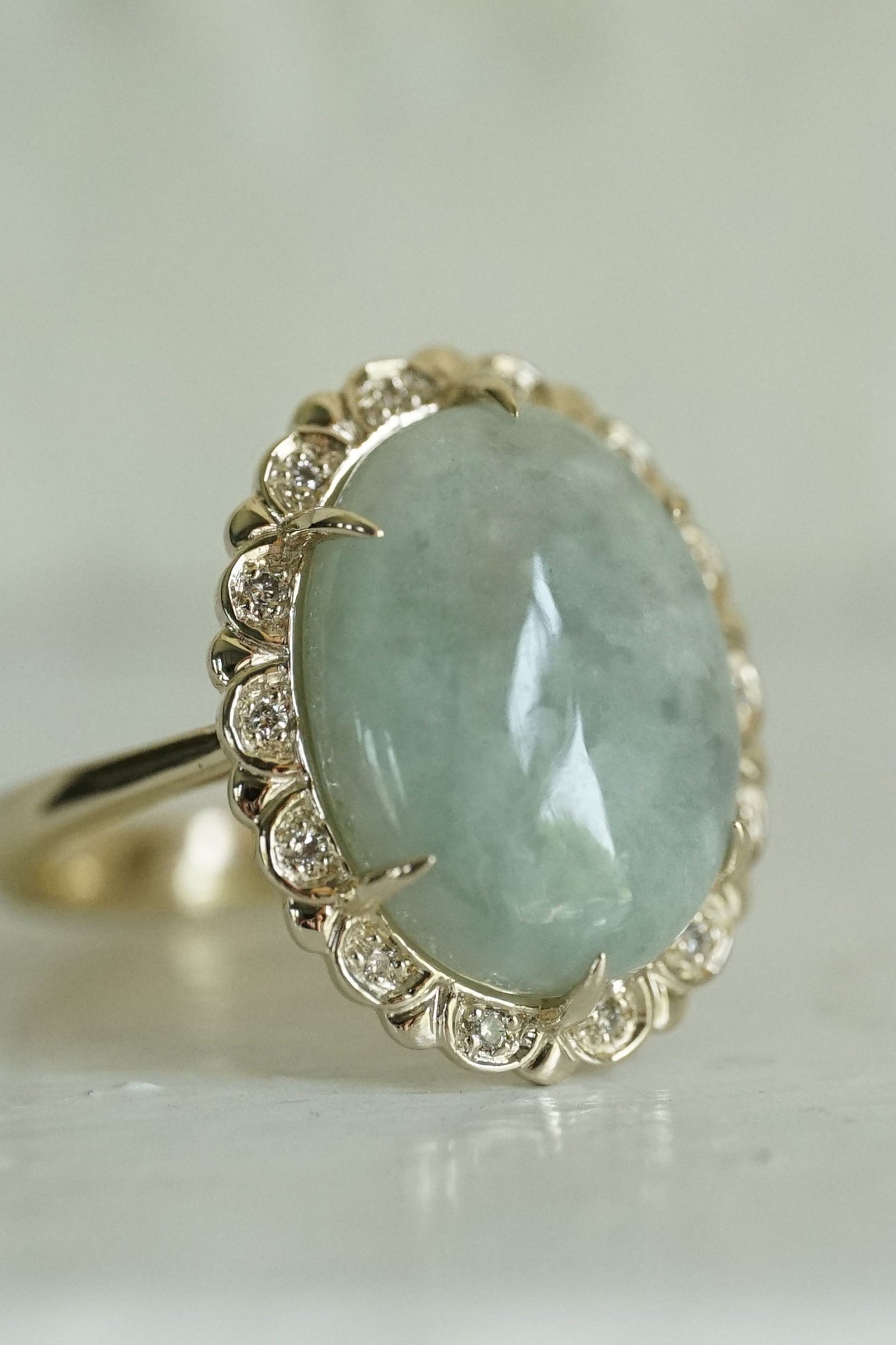 a yellow gold diamond and jade ring on a reflective groundplane