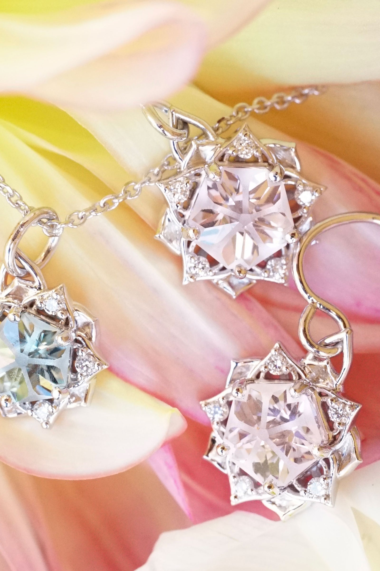 a pair of white gold diamond and pink yag earrings rests on pink and yellow flower petals