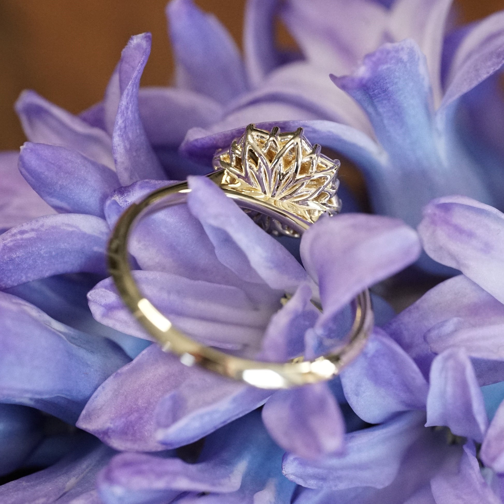 a yellow gold ring featuring a rose cut opal center stone in an 8 prong setting and with a floral diamond halo rotated to show the backside basket design