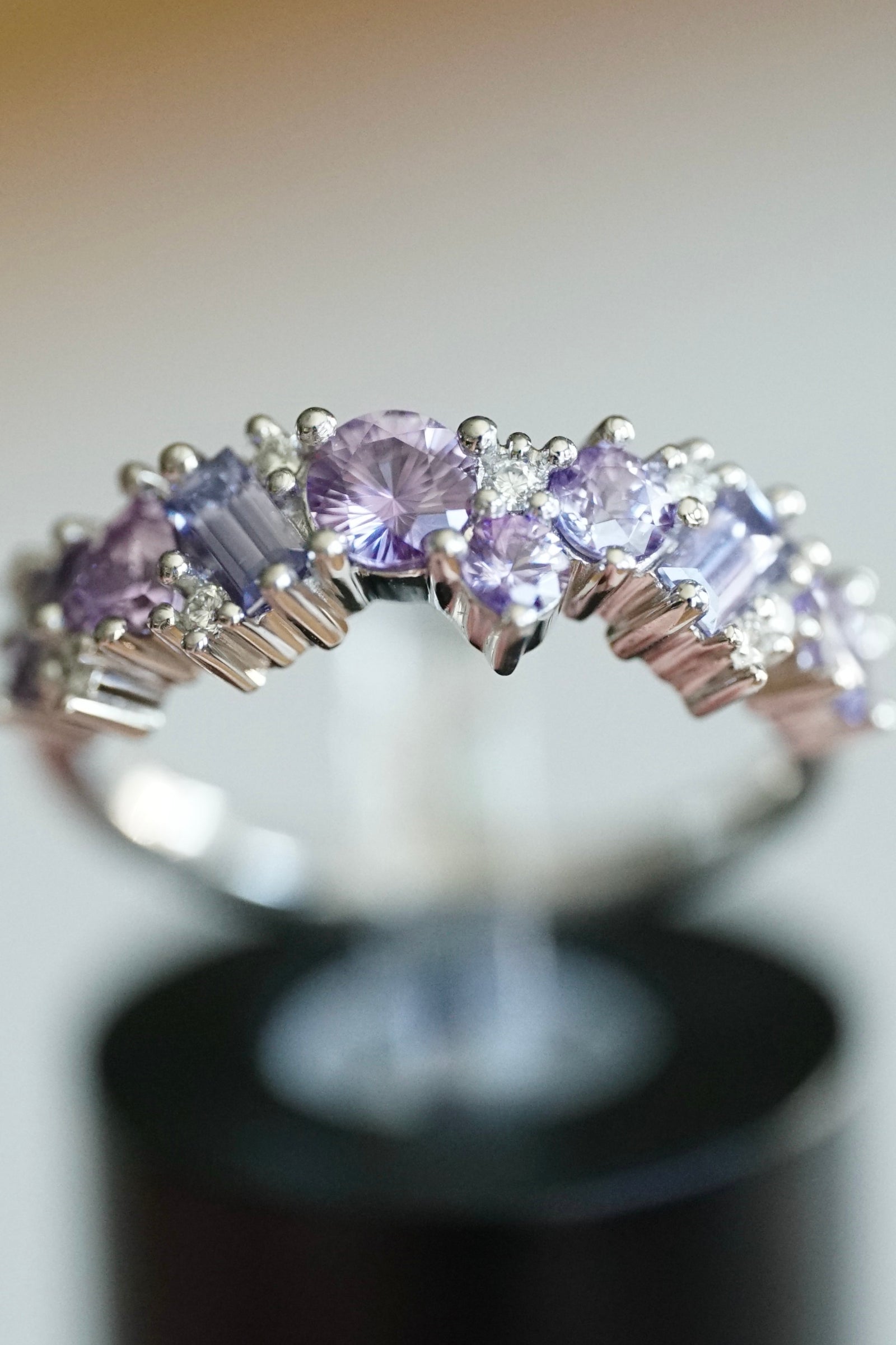 a purple sapphire and diamond ring clipped in a display