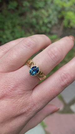 A video of an oval blue engagement ring on a light skin ton left hand next to a wedding band