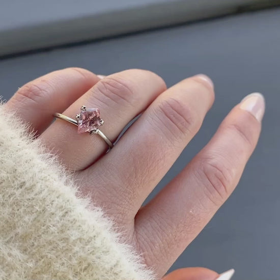 a 1.31 ct unheated orangey pink semi kite shape sapphire in a temporary ring mount in diffused winter sunlight