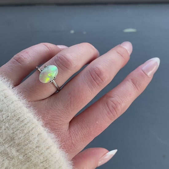 A 2.03 ct oval opal is shown in a temporary ring mount in diffused sunlight