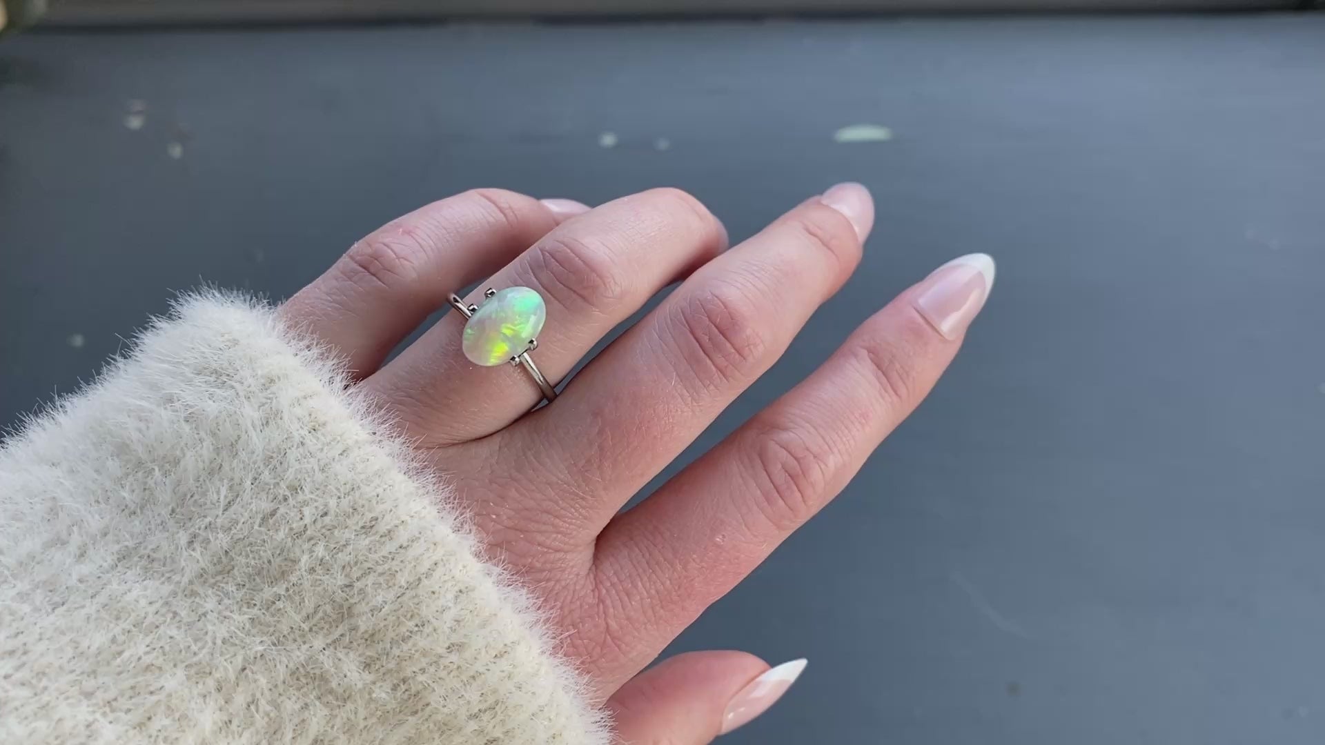 A 2.03 ct oval opal is shown in a temporary ring mount in diffused sunlight