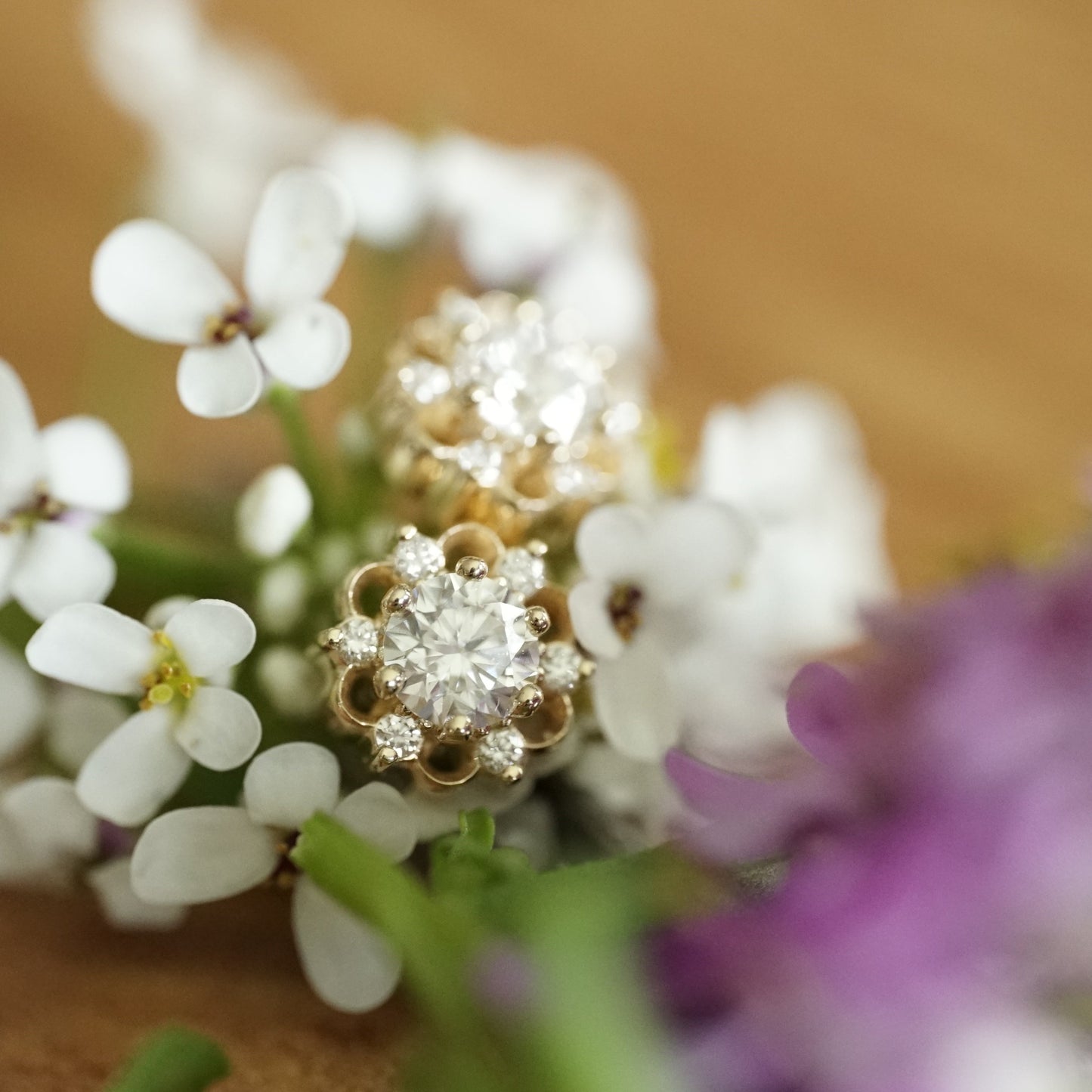 a macro photo of a yellow gold stud earring with a lab ground diamond center stone and 6 natural diamond accents in a floral design