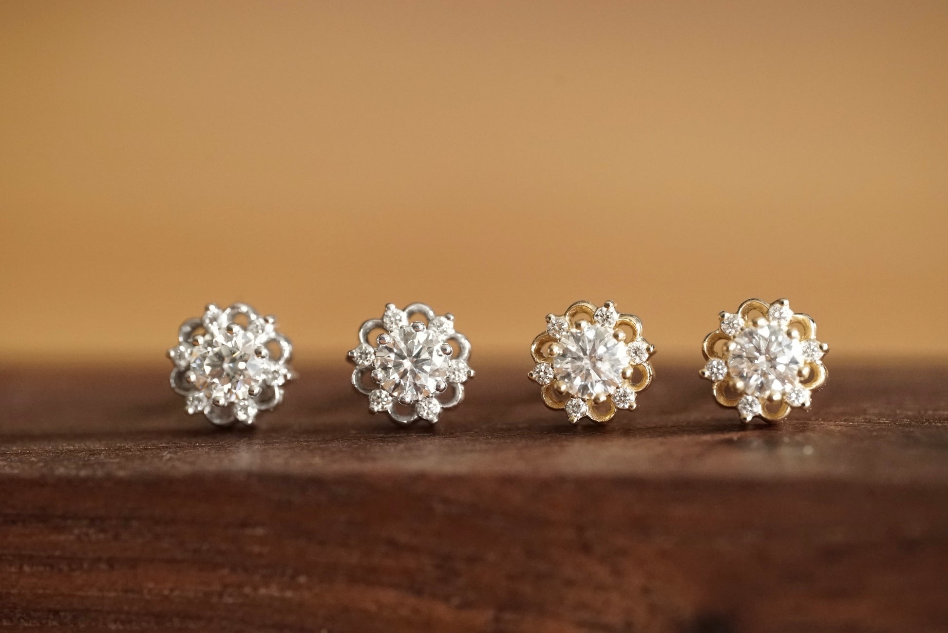 two pairs of lab grown diamond studs, one white and one yellow, side by side on a wood base