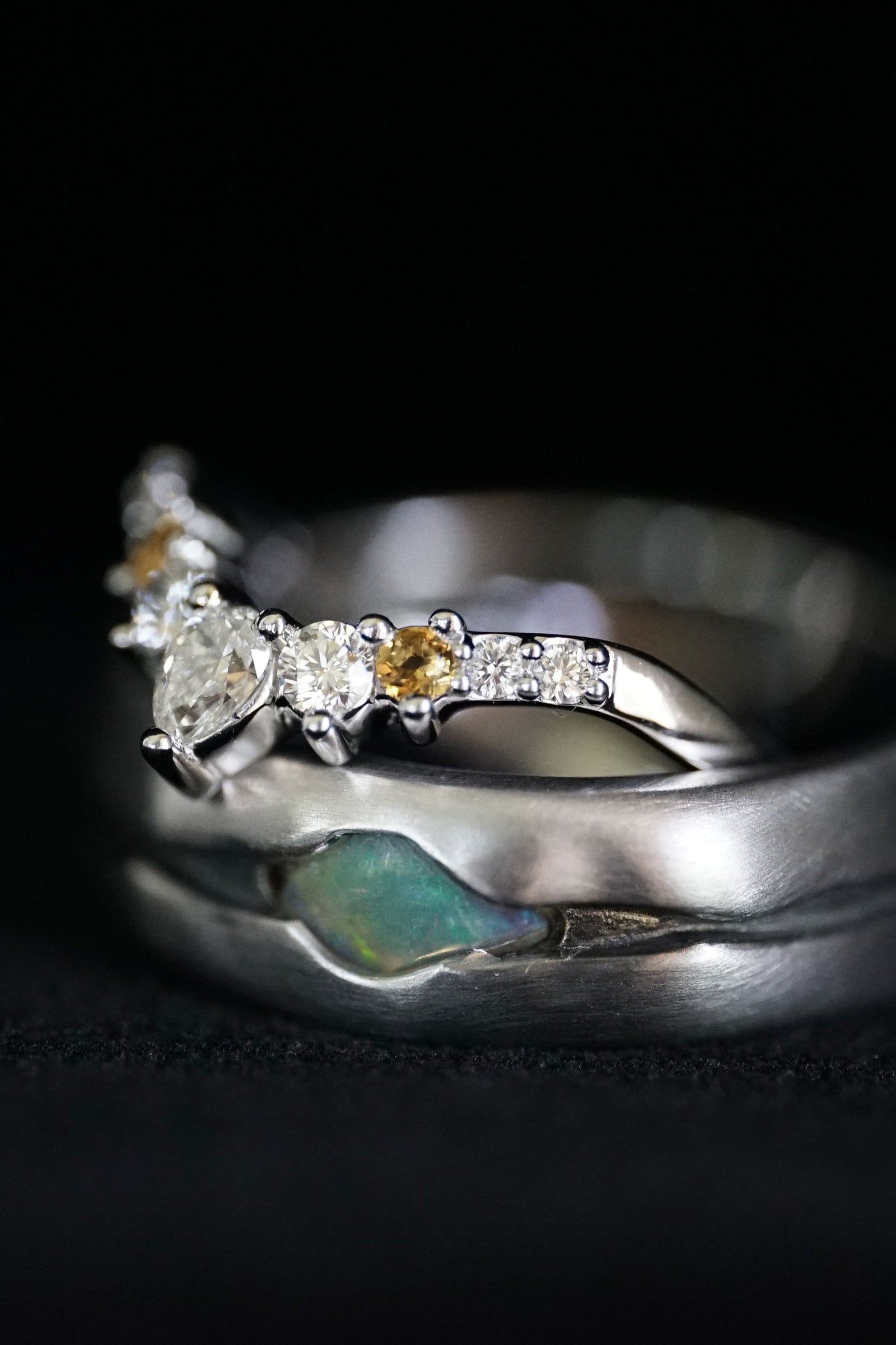 a white gold diamond and opal wedding set on a black background