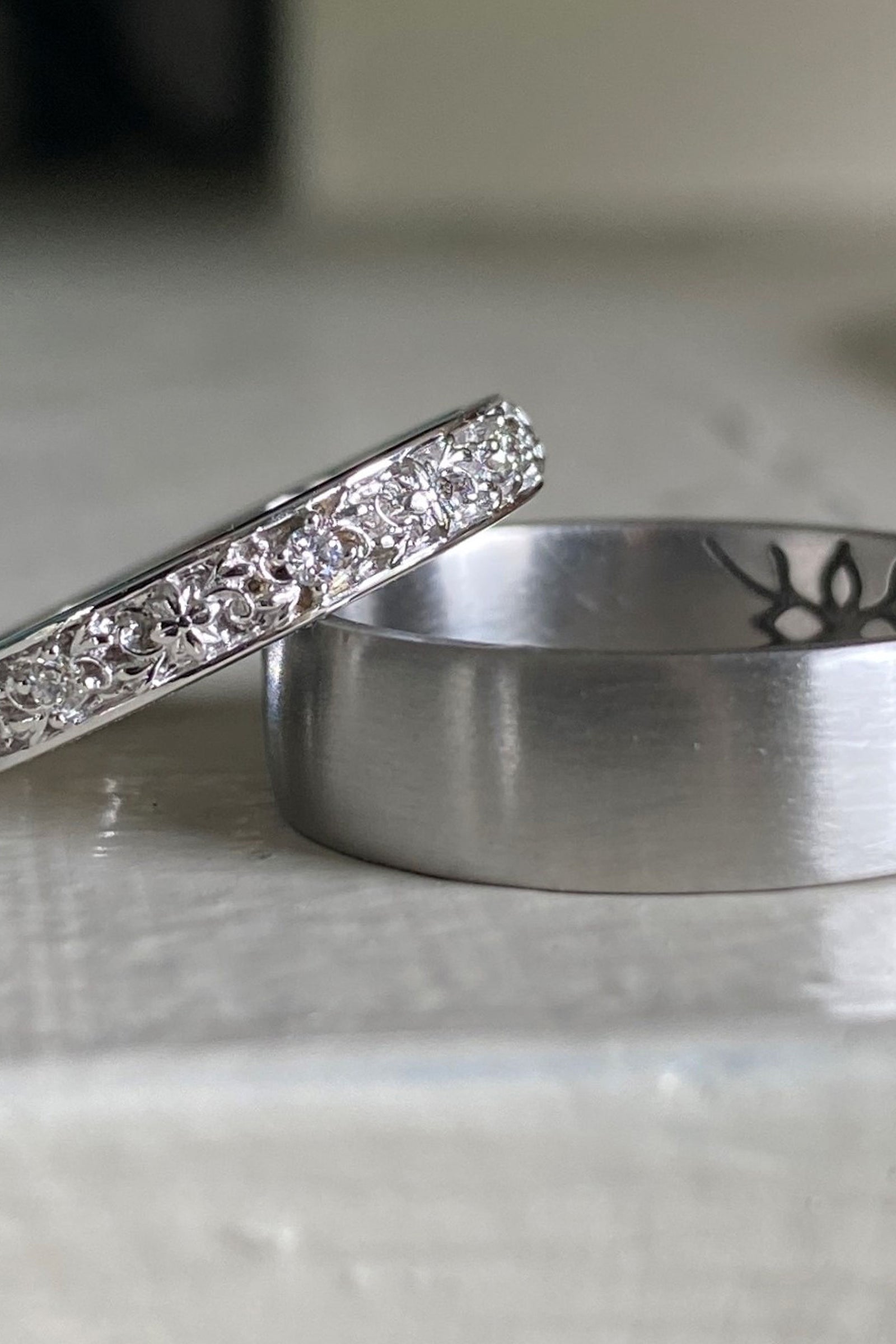 a pair of white gold and diamond wedding bands resting on a white shiny surface