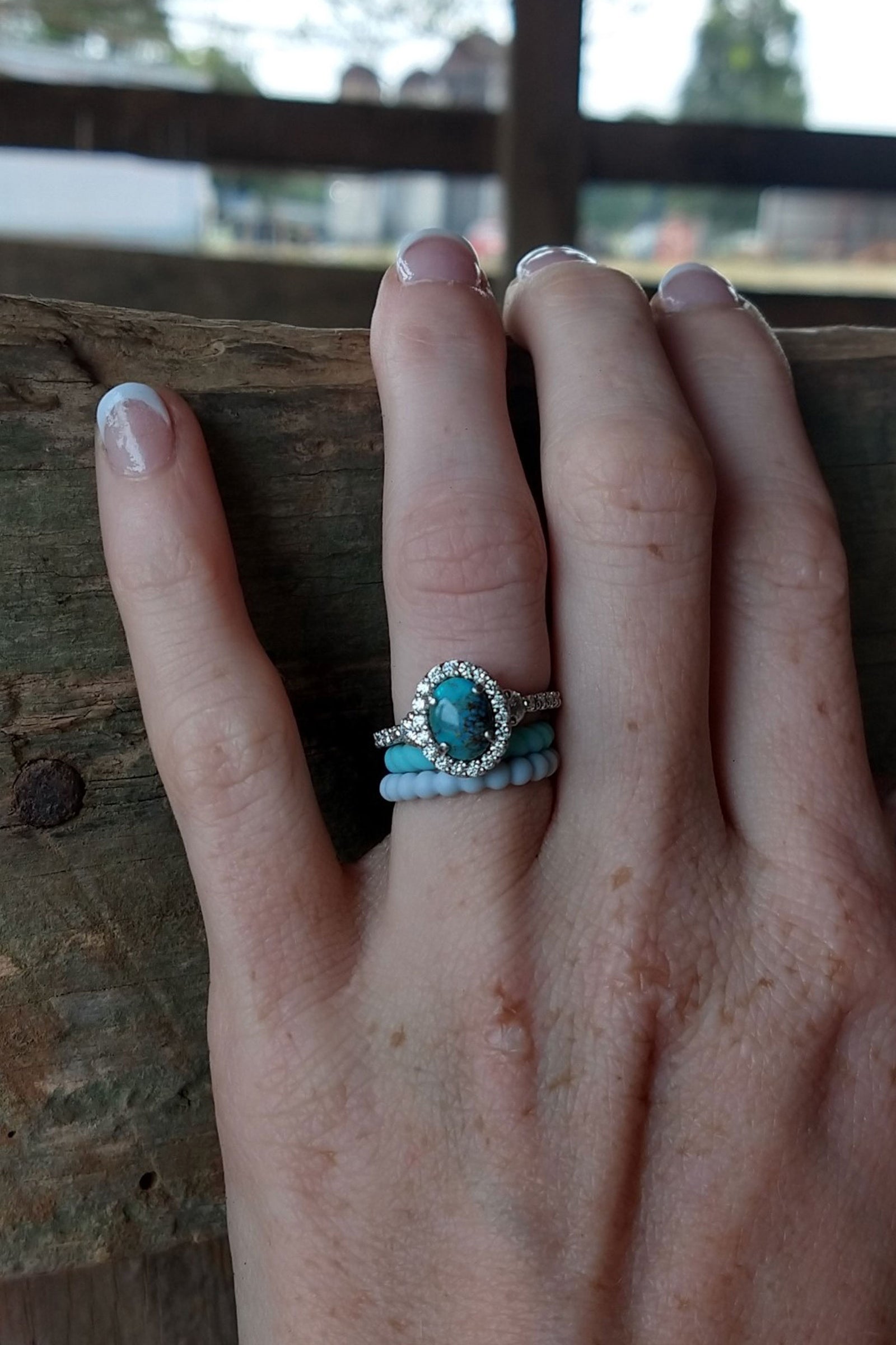 a turquoise and diamond ring on a light skin tone hand