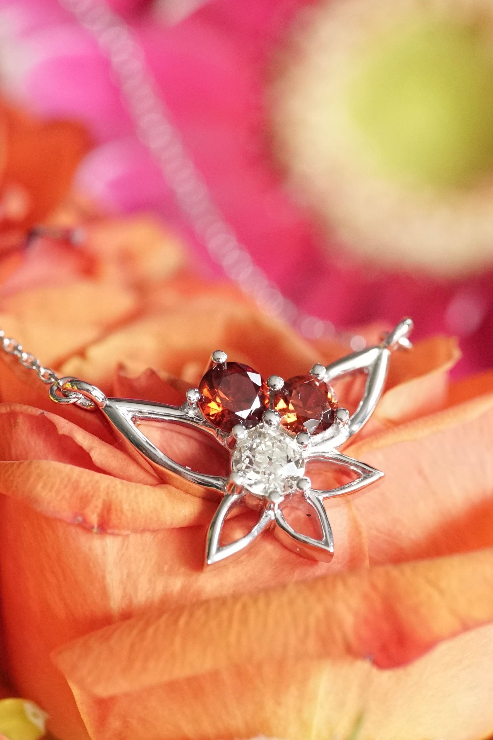 a white gold diamond and garnet necklace on bright orange flowers
