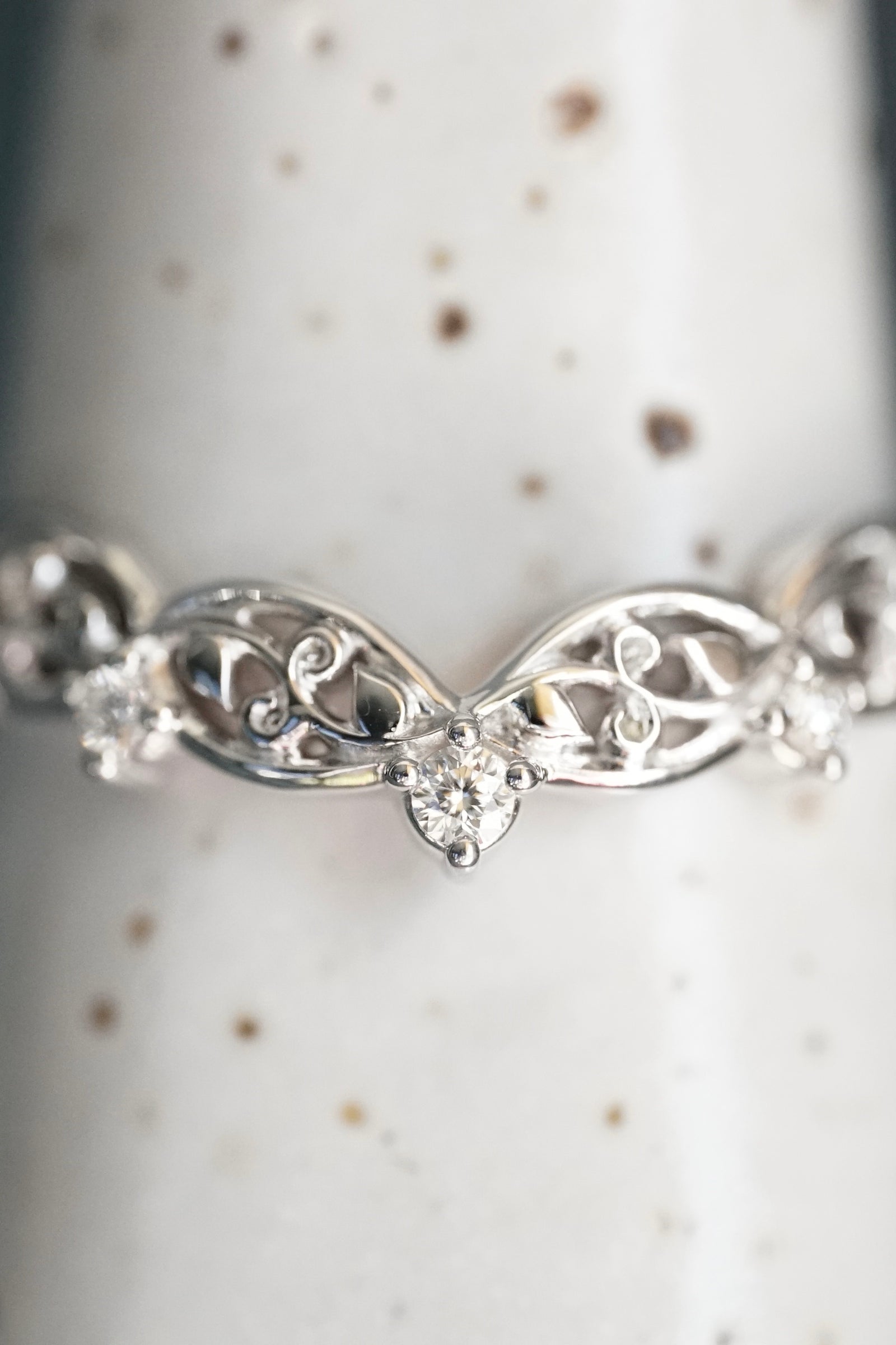 a white gold and diamond wedding band on a white ceramic display