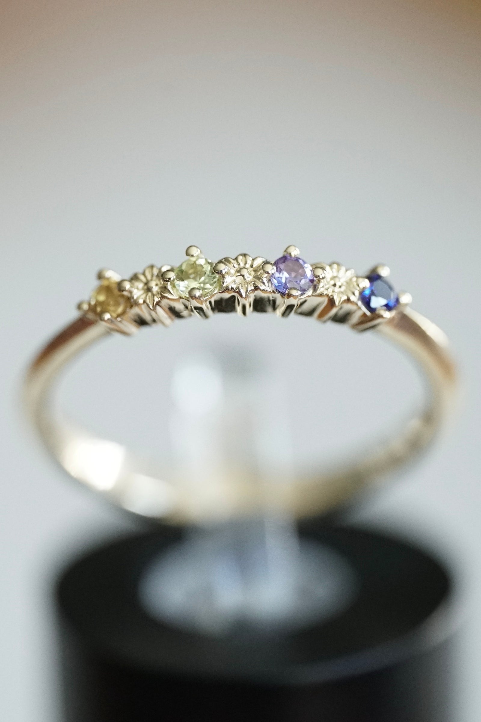 a yellow gold and multi color sapphire ring with small carved flowers between