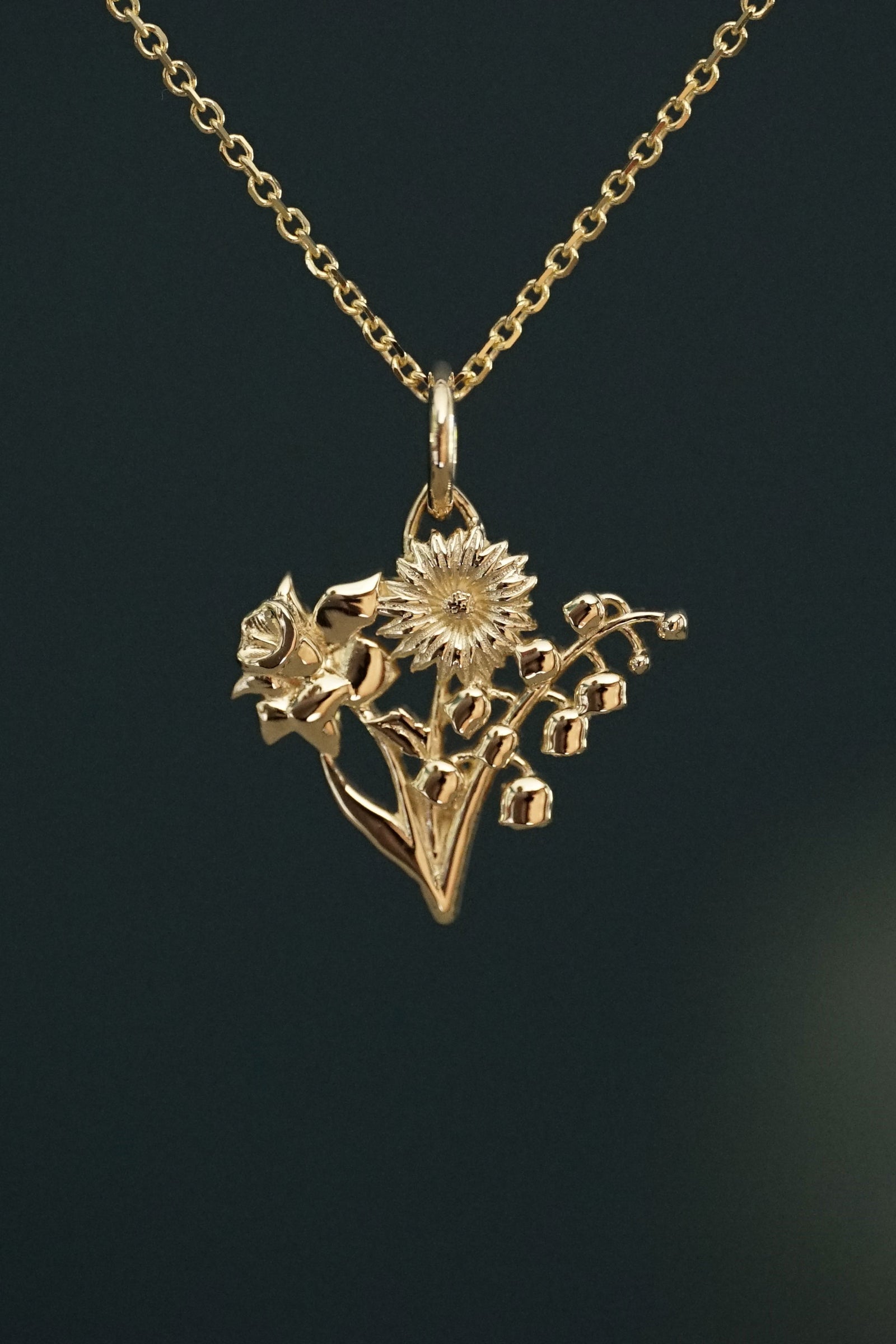 a yellow gold floral bouquet pendant in front of a grey background