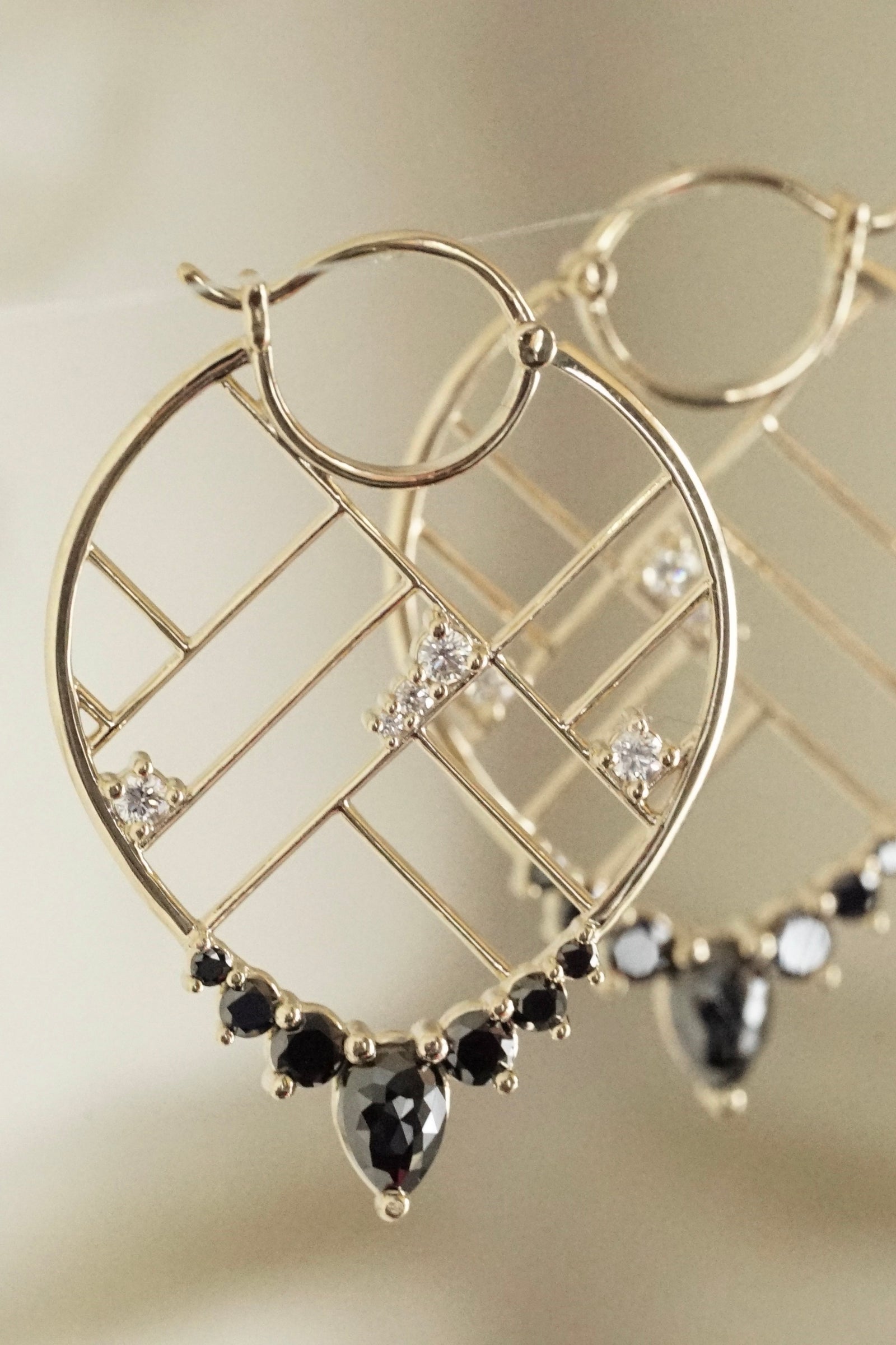 a pair of yellow gold and black and white diamond drop earrings are hanging in a sunny room