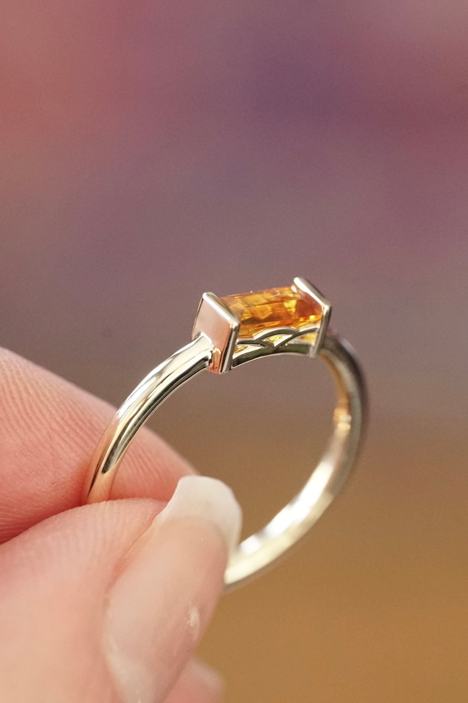 a yellow gold and citrine baguette ring in a light skin tone hand