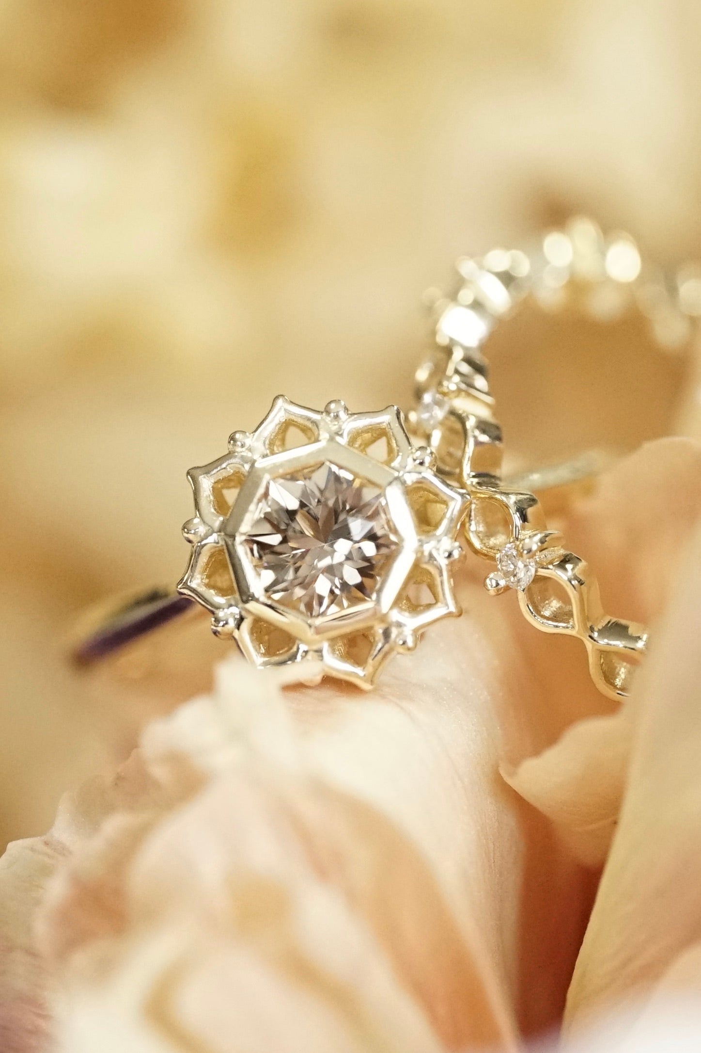 a yellow gold ring with a golden octagonal tourmaline and a yellow gold and diamond band rest in yellow flowers