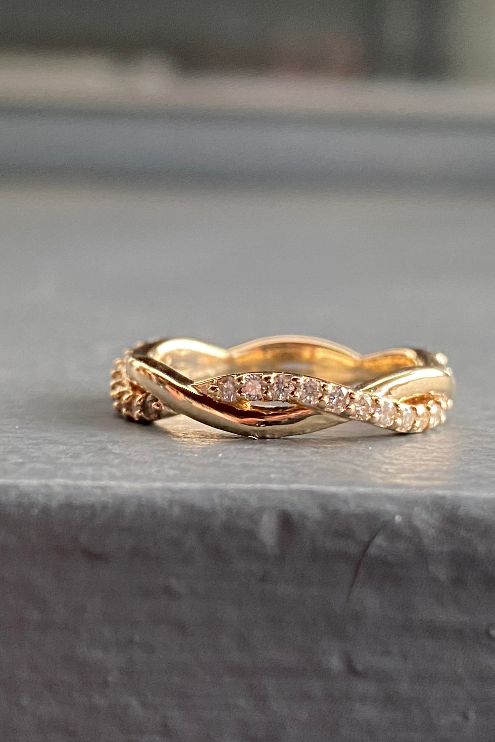 a yellow gold and diamond twisted wedding band on a blue background